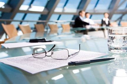 glasses on paper on table next to pen in office meeting
