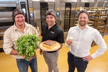 three men inside food factory with alfalfa leaves, cake and white smoothie
