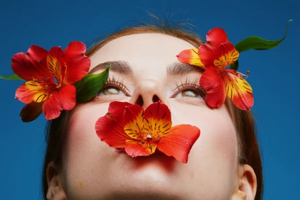 Image A woman with flowers by her eyes and in her mouth.