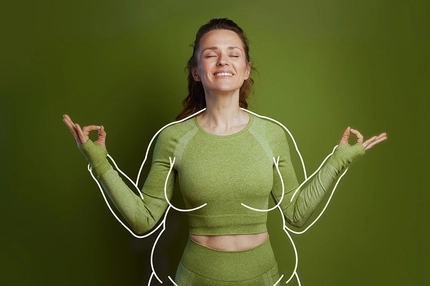 Image Smiling woman in green activewear meditating with eyes closed and hands in a mudra pose against a green background.