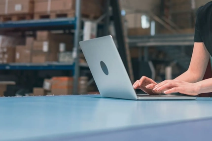 Image A person typing on a computer in a factory