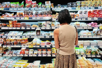 Asian woman in supermarket selecting food products.