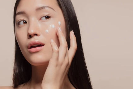 Image A woman with three dots of cream on her face.
