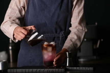 Female barista making cold brew coffee at table,