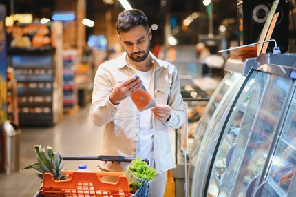 Image Man shopping for groceries examining a food label in the supermarket.