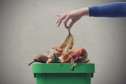 Image Woman putting organic waste in the recycling bin