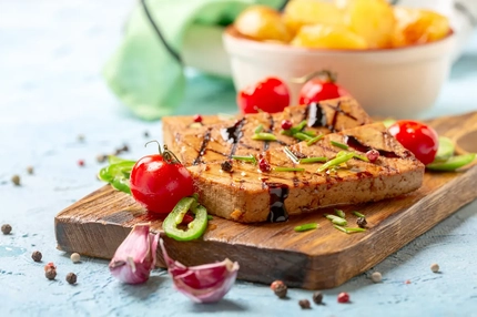 Image Plant-based hybrid meat on a cutting board with vegetables.