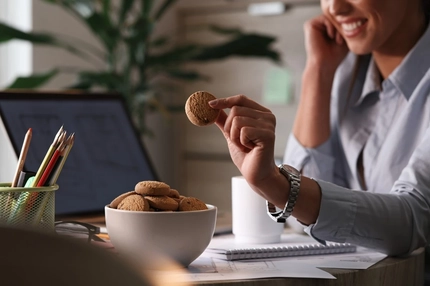 Image Female worker having cookies for a snack in the office.