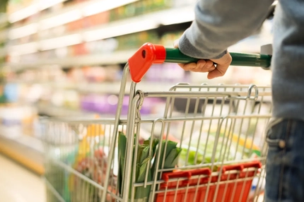 A person pushing a grocery cart through a store.