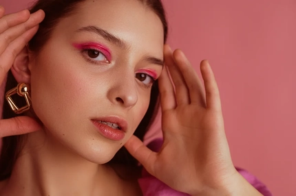 A woman wearing makeup and holding her face.