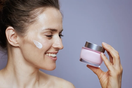 Image A woman holding a pot of skin cream.