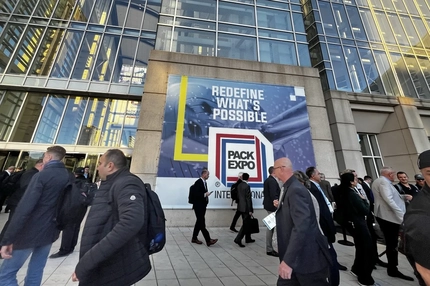 Image a sign outside of a building with people passing by