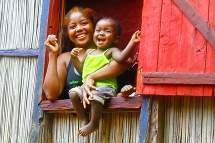 Image happy mother hold her child, who sits on a window sill