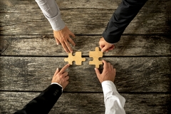 Image Four successful business men joining two puzzle