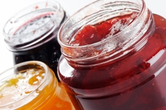 Image Open jars of assorted fruit jams in red, orange, and dark purple colors