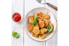 Image A bowl of chicken nuggets topped with ketchup and basil leaves