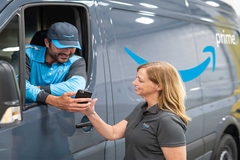 Image Two Amazon workers looking at a phone by a delivery van