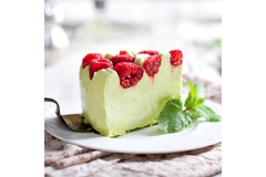 Slice of green matcha cake topped with fresh raspberries and mint