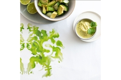 Image Bowl of avocado cubes with lime and creamy avocado dip, styled with artistic green pattern on white tablecloth