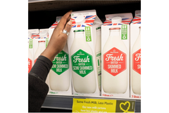 A person taking out a carton of fresh milk out of the shelf.
