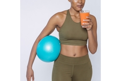 A woman in workout clothes drink a carrot smoothie.
