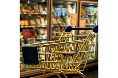Golden shopping cart in supermarket aisle with blurred grocery shelves in background