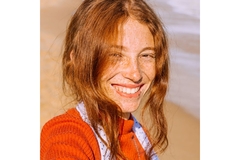 Image A smiling woman with freckles on her face looks directly at the camera.