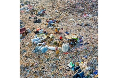 Image landfill with scattered waste, makeshift shelters, and people collecting recyclables