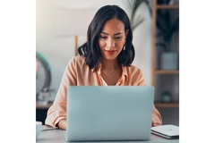 Image smart, confident woman of African descent working on laptop while giving a half smile.