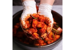 Image A person holding freshly made kimchi in their laytex gloved hands.