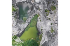 A green body of inland water surrounded by gray rocky terrain.