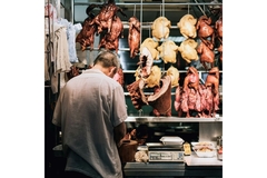 Image Asian man standing in front of display of various meats
