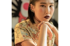 A Chinese woman wearing a traditional Chinese blouse poses for the camera.