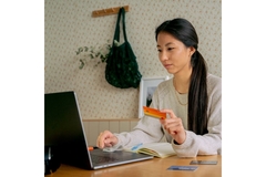 Image Person shopping behind a computer with bank card in hand.