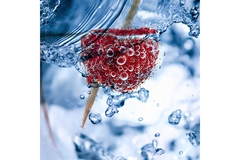 A raspberry floats in sparkling water.