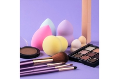 Image A collection of makeup items comprising a cosmetic palette, makeup brushes, cosmetic powders and beauty blenders.
