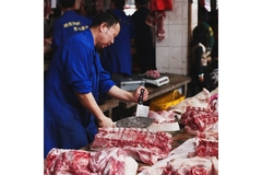 Image Man standing between different red meats.