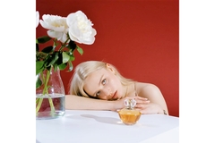 Image woman leans on table with perfume and flowers