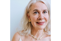 An elderly woman with white hair smiles.