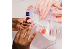 A nail salon technician helps a woman choose her nail color from a swatch.