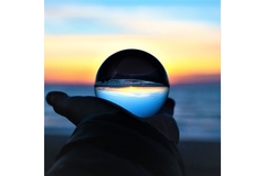 Image A person holds a crystal ball and looks at the sea.