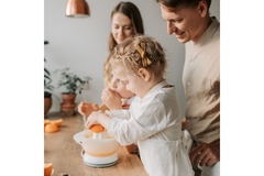 Image Girl squeezing orange juice with her parents.
