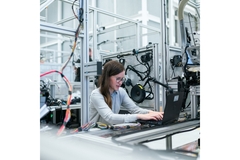 Image woman works on a laptop in a factory setting