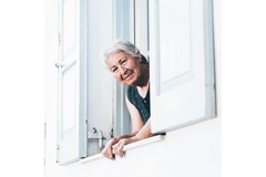 Image Elderly woman standing by her window