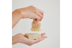 A person's hands holding up a bar of soap and a soap brush.
