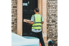 delivery man outside a house with an amazon package in hand