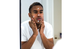 Image man looking at himself in the mirror while applying face cream