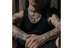 Image A man with tattoos on his chest and arms.