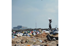 Image person carrying a bag on their head leaving a garbage dump