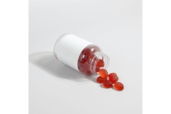 Image red gummy supplements spilling from bottle